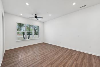 A room with a ceiling fan and a window with blinds.